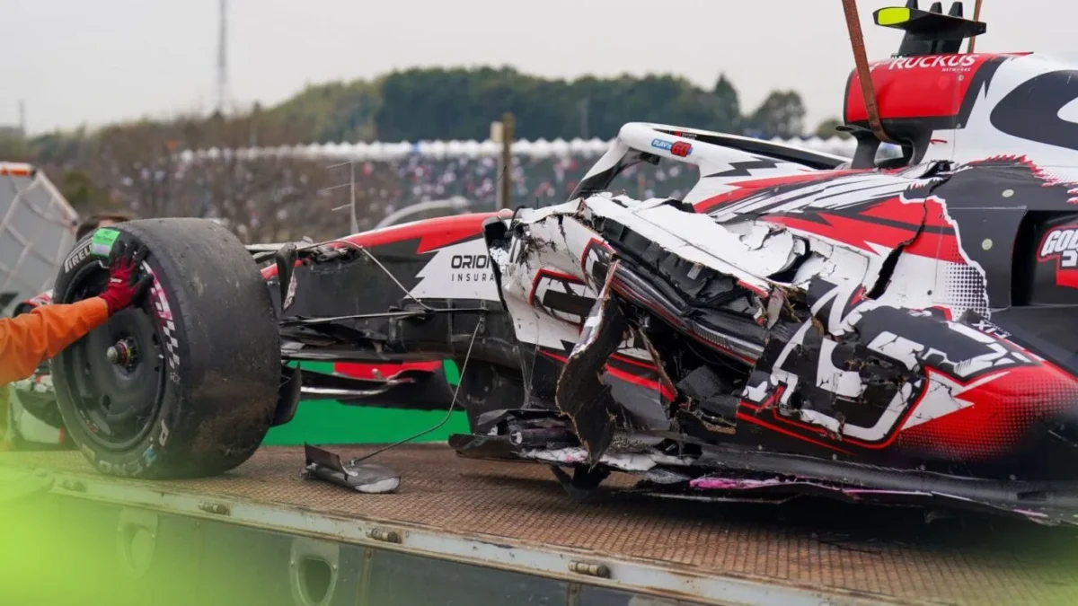Oliver Bearman's damaged Haas VF-26 sits against the barriers at Suzuka's Spoon Curve following his 50G crash during the 2026 Japanese Grand Prix, with marshals approaching the wreckage.