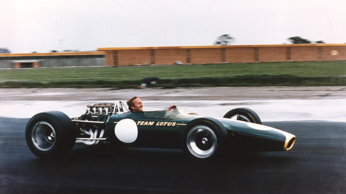 Colin Chapman stands beside the Lotus 49 Formula One car in 1967, the year it introduced the stressed-member engine concept that transformed F1 chassis design