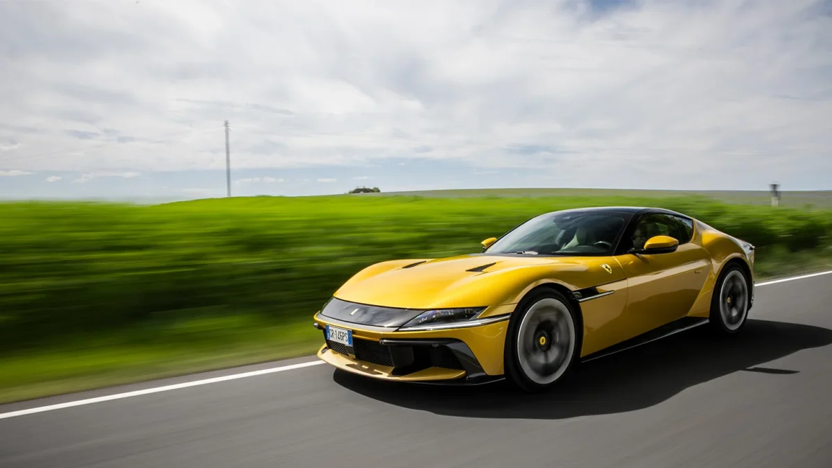 A yellow Ferrari 12Cilindri grand tourer, showing its fastback profile, long bonnet and rear-wheel-drive stance during a review.