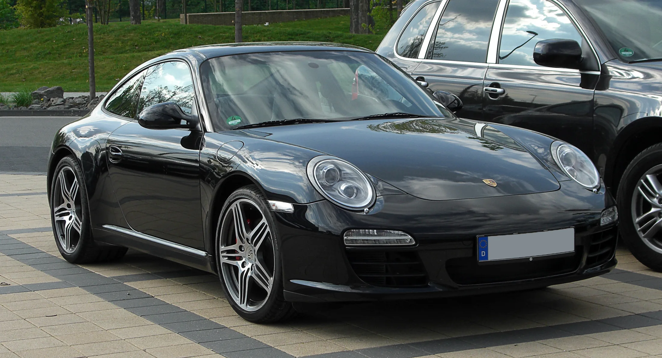 A Porsche 997.2 911 Carrera S coupe in Black with a manual gearbox parked on a clean tarmac surface, representing the last analogue generation of the iconic sports car.