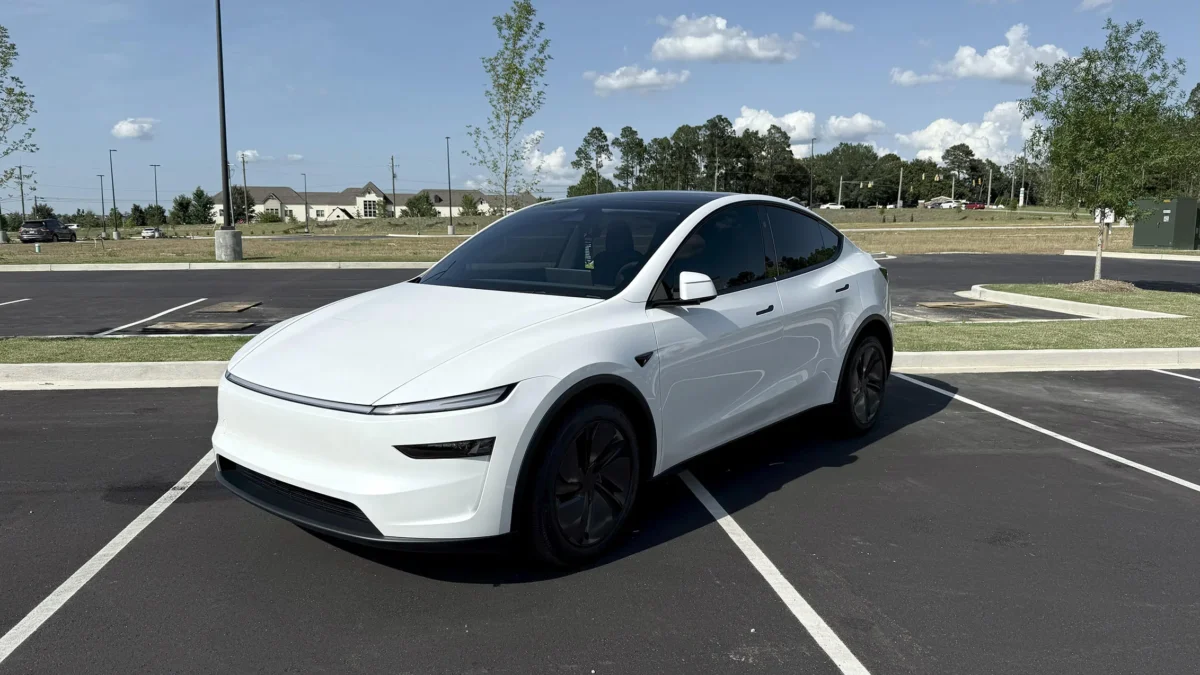 The 2026 Tesla Model Y in white showing the redesigned slim headlights and updated front fascia of the Juniper refresh, parked on a clean surface against a neutral background.