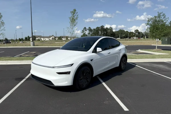 The 2026 Tesla Model Y in white showing the redesigned slim headlights and updated front fascia of the Juniper refresh, parked on a clean surface against a neutral background.