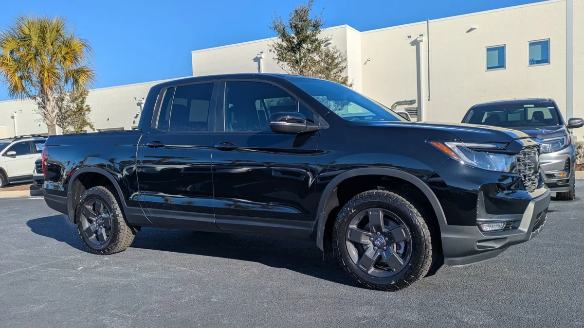A Honda Ridgeline TrailSport pickup truck parked at a Honda dealership lot, representing the model that will be pulled from production until late 2028 due to emissions standards.