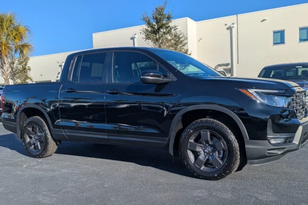 A Honda Ridgeline TrailSport pickup truck parked at a Honda dealership lot, representing the model that will be pulled from production until late 2028 due to emissions standards.