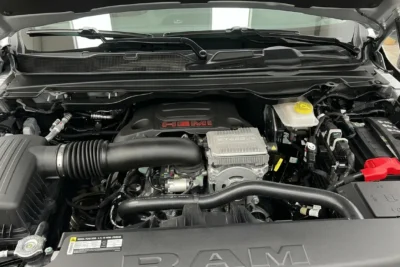 A 2026 Ram 1500 pickup truck displayed with a close-up of its Hemi V8 engine badge, illustrating the engine's return to Stellantis' core lineup after being discontinued in 2024.