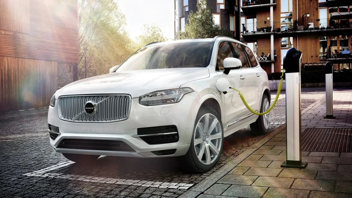 A Volvo XC90 plug-in hybrid SUV photographed alongside a Volvo Trucks heavy goods vehicle, illustrating the contrasting powertrain strategies of the two Volvo companies.