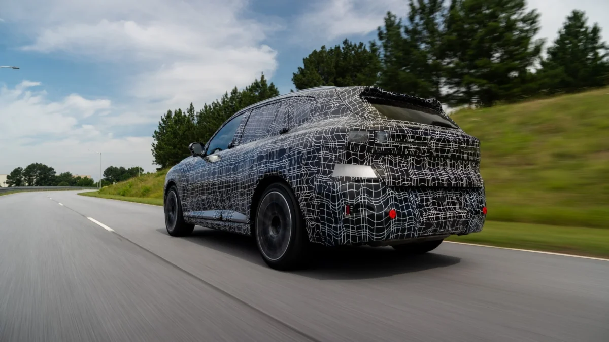 A 2027 BMW X5 G65 luxury SUV in pre-production camouflage being tested at BMW's Plant Spartanburg in South Carolina ahead of its August 2026 production launch with five powertrain options.