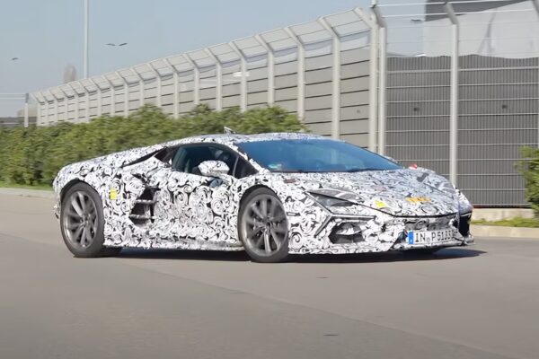 A Lamborghini Revuelto SV prototype wrapped in black-and-white swirl camouflage being driven on a public road near the factory in Italy, captured during development testing ahead of its 2026 reveal.