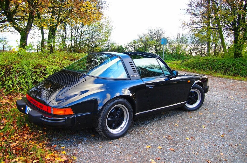 A 1980s Porsche 911 SC on an open road, representing the generation of 911 that CEO Peter Schutz saved from cancellation in 1981 when he overruled Porsche's plan to replace it with the 928