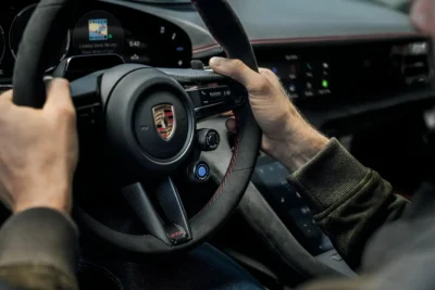 The 2027 Porsche Taycan electric sedan interior showing the GT Sport steering wheel with paddle shifters and virtual rev counter for the new E-Shift simulated eight-speed gearbox system.