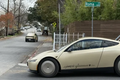 A Tesla Cybercab autonomous robotaxi driving without a driver on an Austin Texas street, representing Tesla’s expansion of its unsupervised robotaxi service across the entire Austin metropolitan area in June 2026.