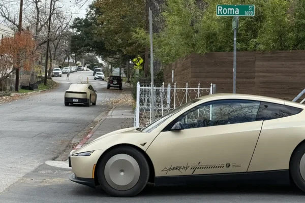 A Tesla Cybercab autonomous robotaxi driving without a driver on an Austin Texas street, representing Tesla’s expansion of its unsupervised robotaxi service across the entire Austin metropolitan area in June 2026.