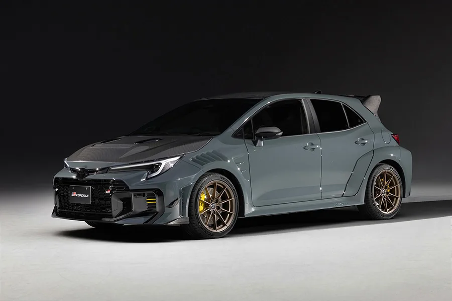 A 2026 Toyota GRMN Corolla compact hatchback in white with carbon-fibre aero parts and an adjustable rear wing, photographed on track at the Nürburgring during GAZOO Racing development testing.