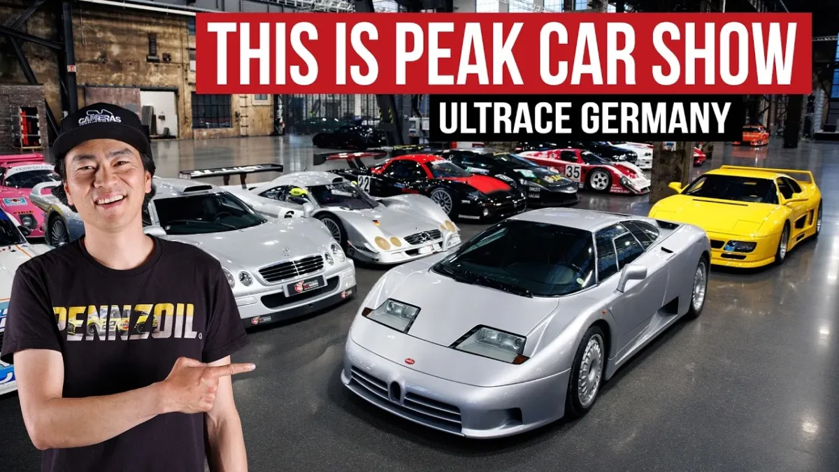 Larry Chen stands in the industrial halls of Ultrace Germany 2026 at the Areal Böhler in Düsseldorf, pointing toward a collection of rare cars including a silver Bugatti EB110, a Mercedes-Benz CLK GTR street car, a yellow Ferrari F40, and several GT1-era Le Mans prototype race cars displayed on the polished concrete floor behind him.