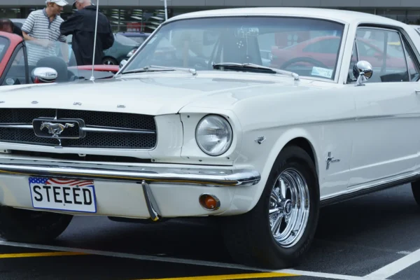 A 1964 Ford Mustang hardtop in Wimbledon White at its World's Fair launch, the car Lee Iacocca convinced Henry Ford II to greenlight in a pivotal 1962 product planning meeting