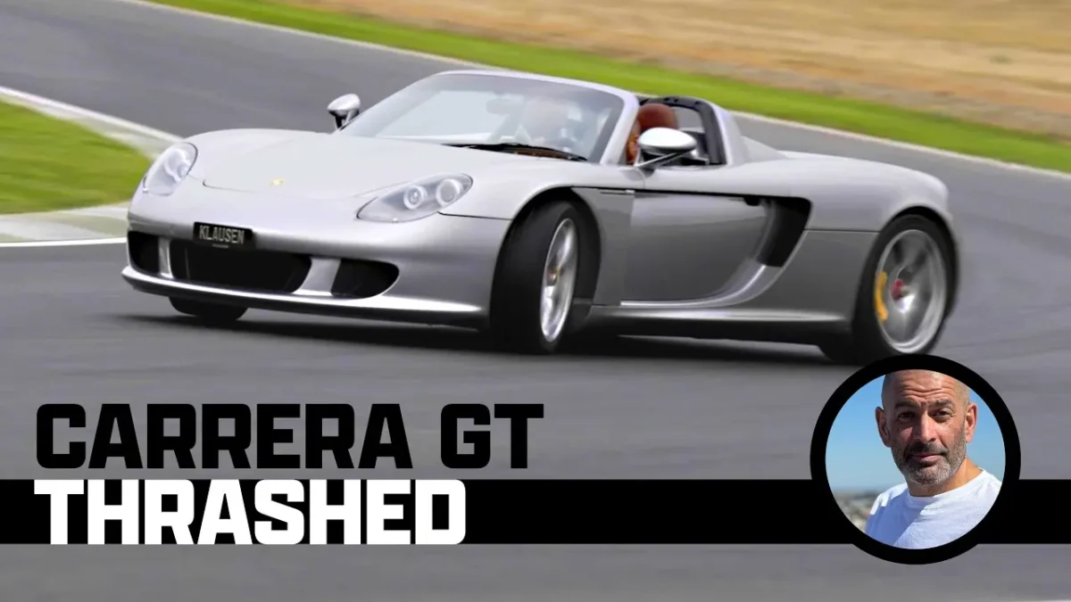 A Porsche Carrera GT on track at the Ascari Circuit in Spain on a damp surface showing the rear spoiler raised and the V10 supercar in motion.